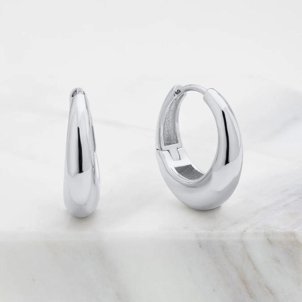 Pair of silver hoop earrings on a light marble surface