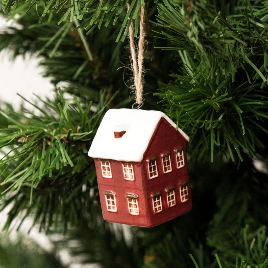 Red house ornament with snow on a Christmas tree