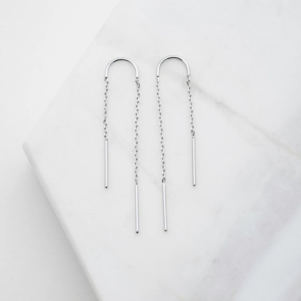 Pair of silver threader earrings on a light gray background