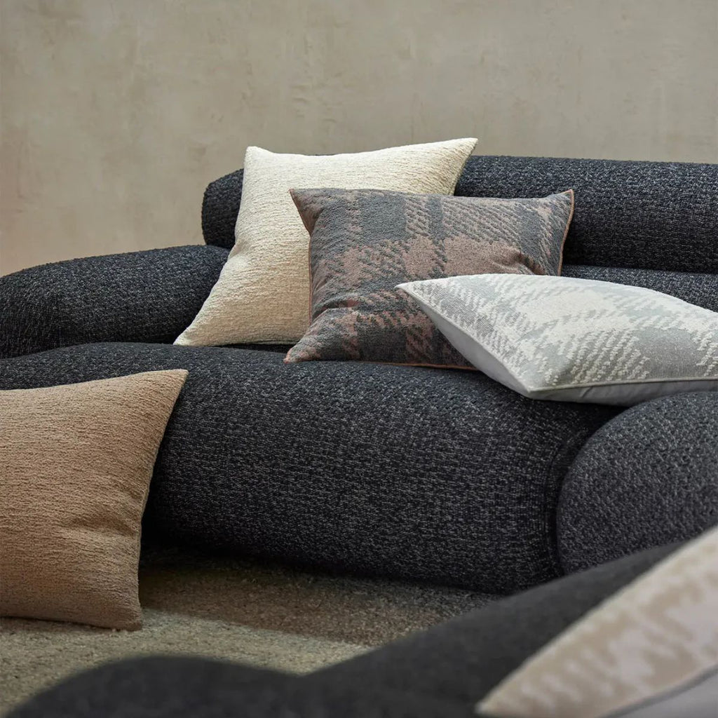 Gray sofa with patterned cushions against a neutral wall