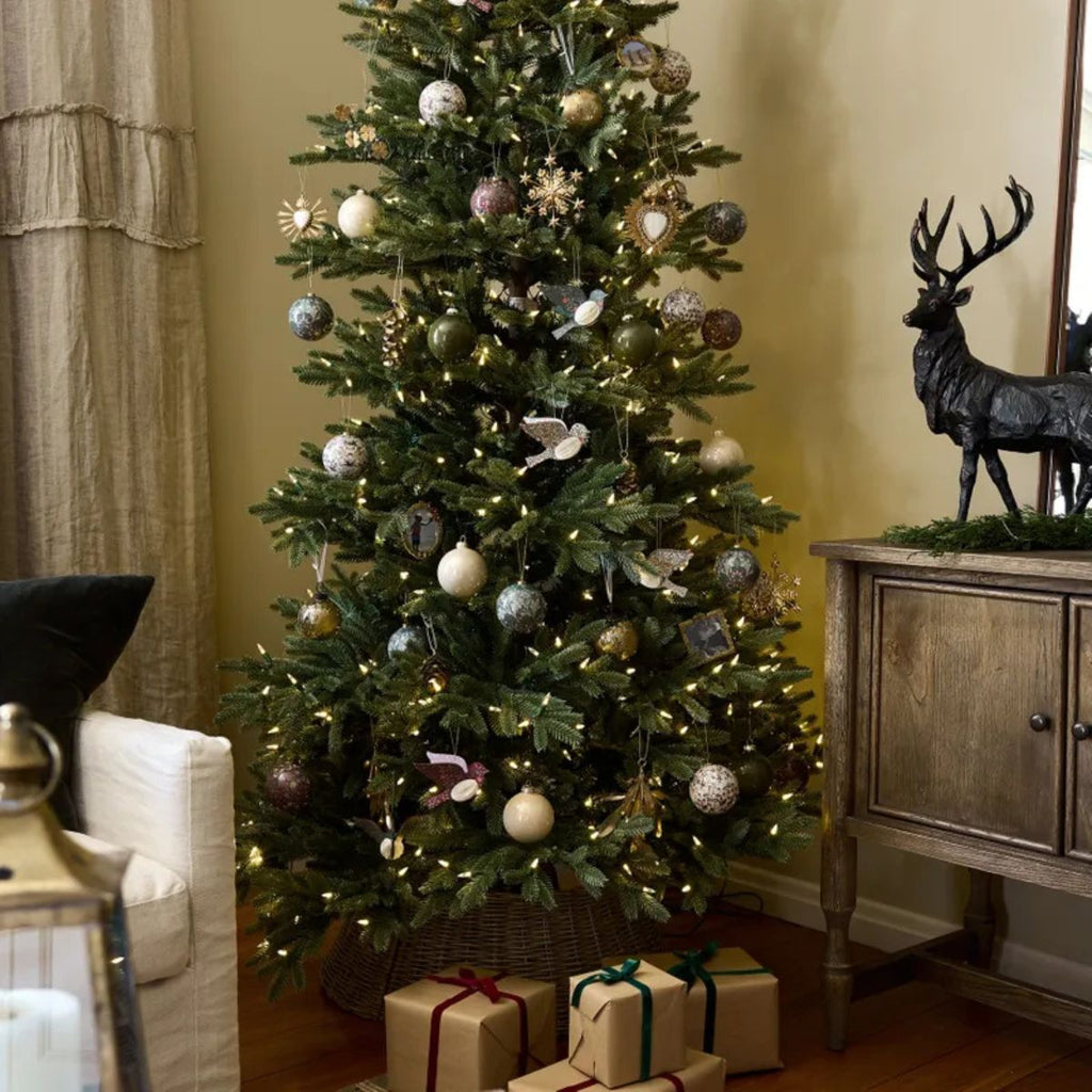 Decorated Christmas tree with ornaments and lights in a living room setting.