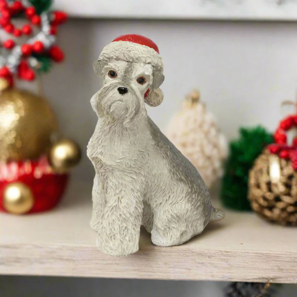 Dog figurine wearing a Santa hat on a shelf with Christmas decorations.
