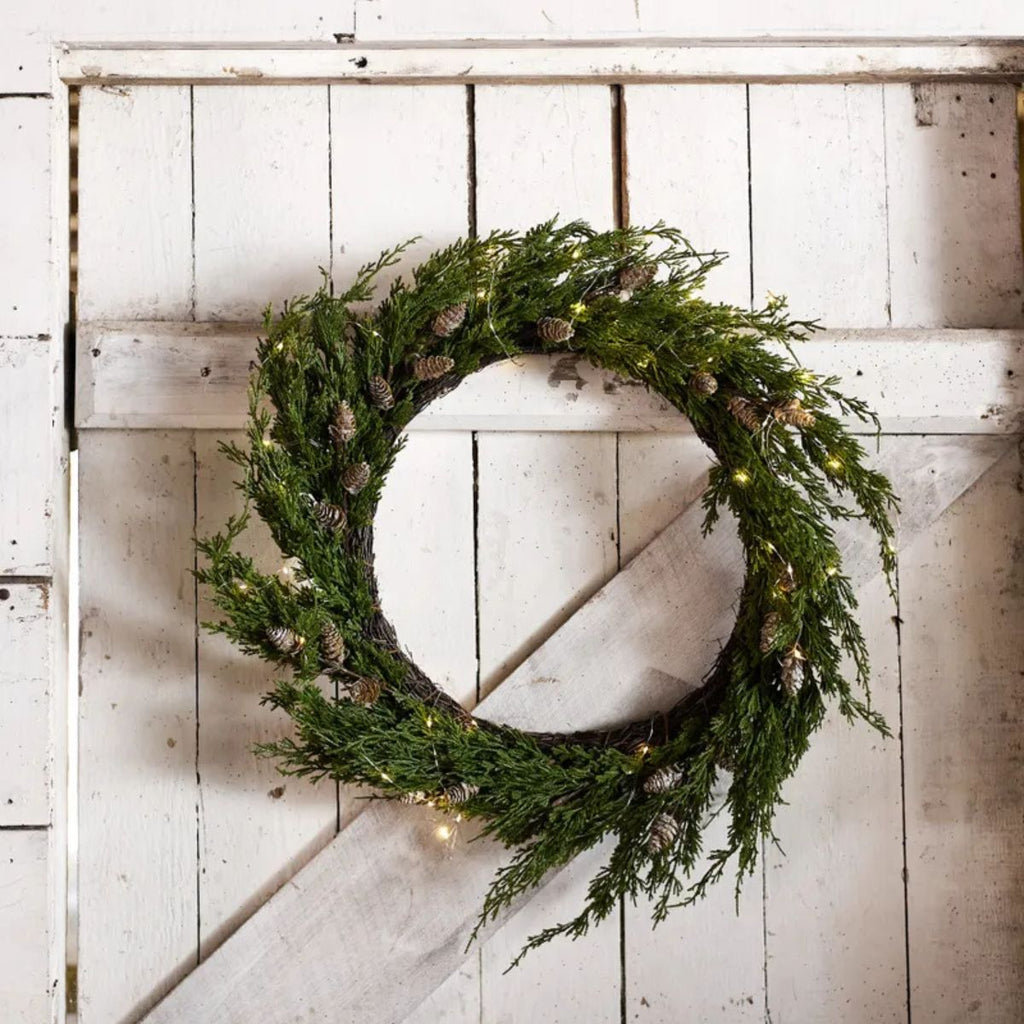 Green wreath with lights on a white wooden background