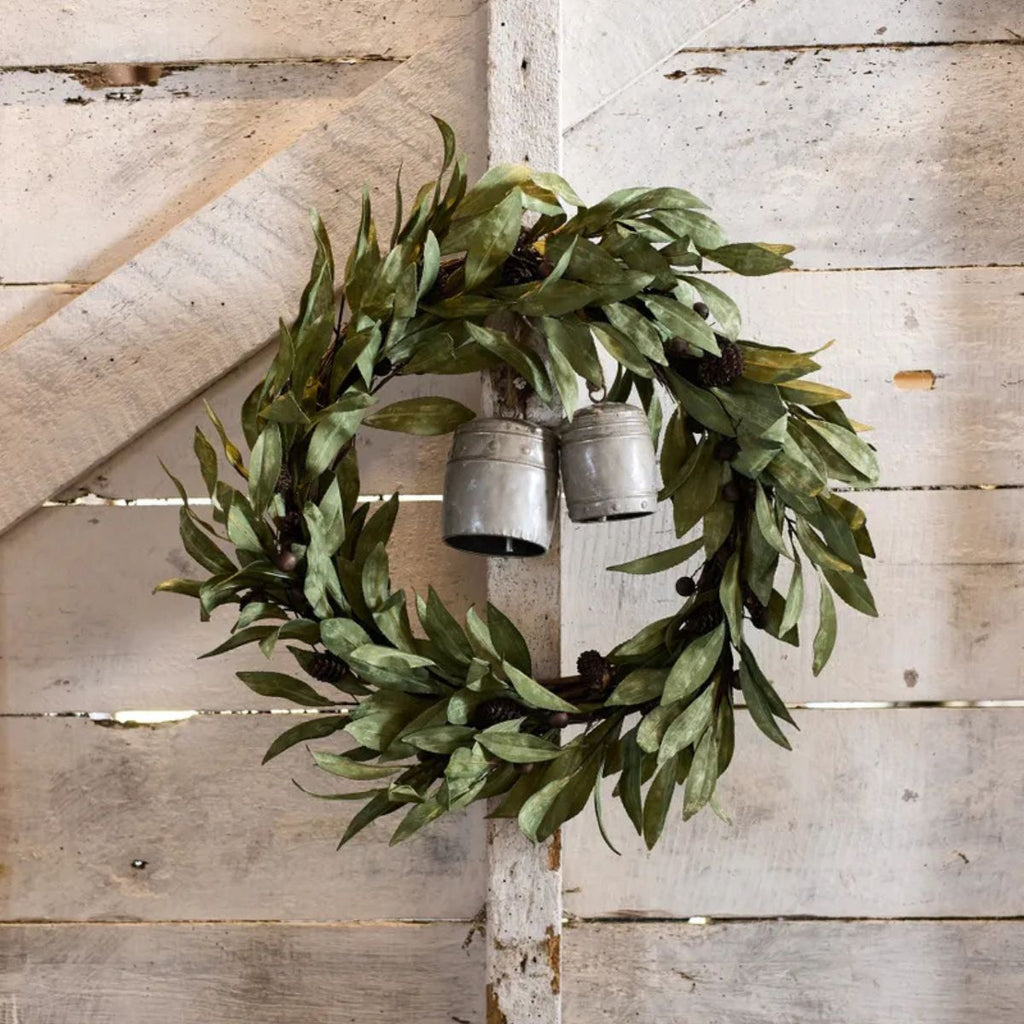 Green leafy wreath with metal bells on a wooden wall