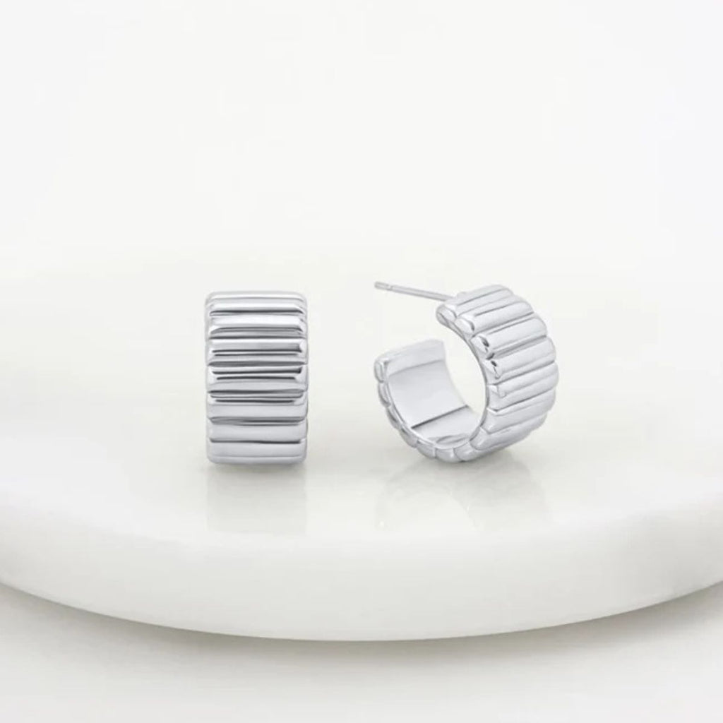 Pair of silver hoop earrings on a white plate