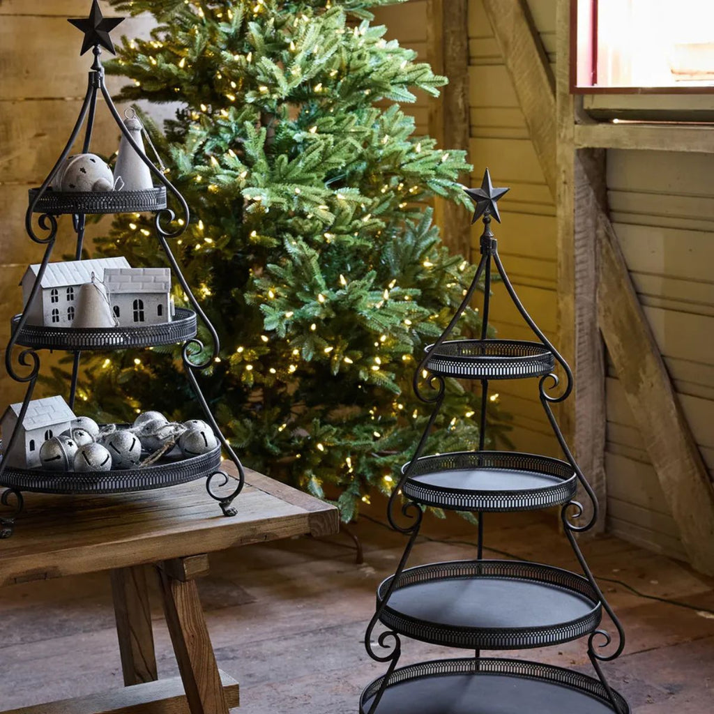 Decorative metal tiered stands with small houses and a Christmas tree in the background.