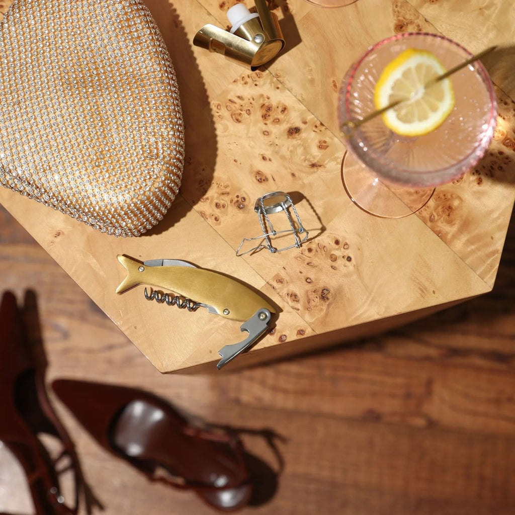 Cocktail glass with lemon slice, corkscrew, and decorative item on a wooden surface