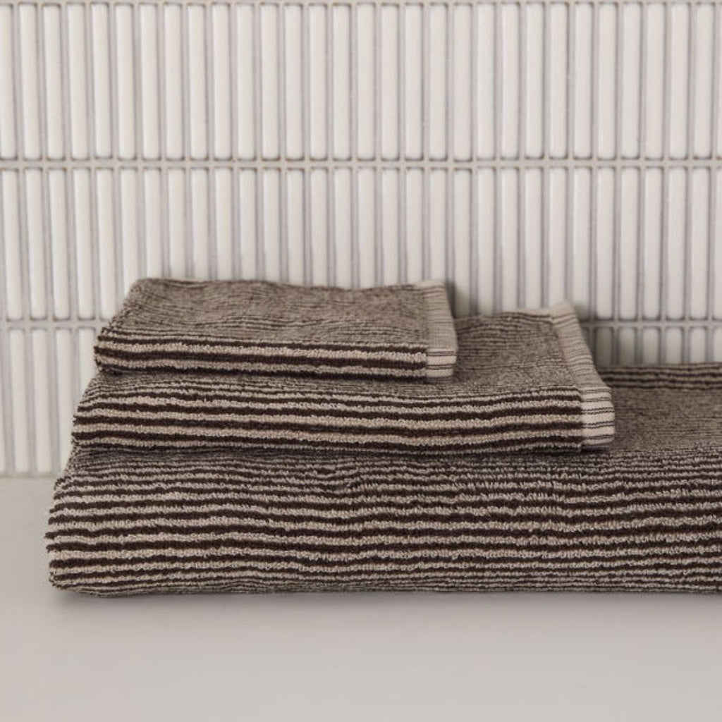 stack of brown and cream striped towels against a neutral background
