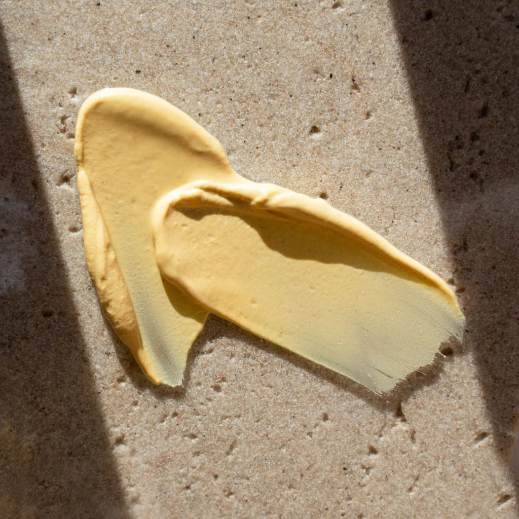 Yellow smear of facial mask on a textured beige surface