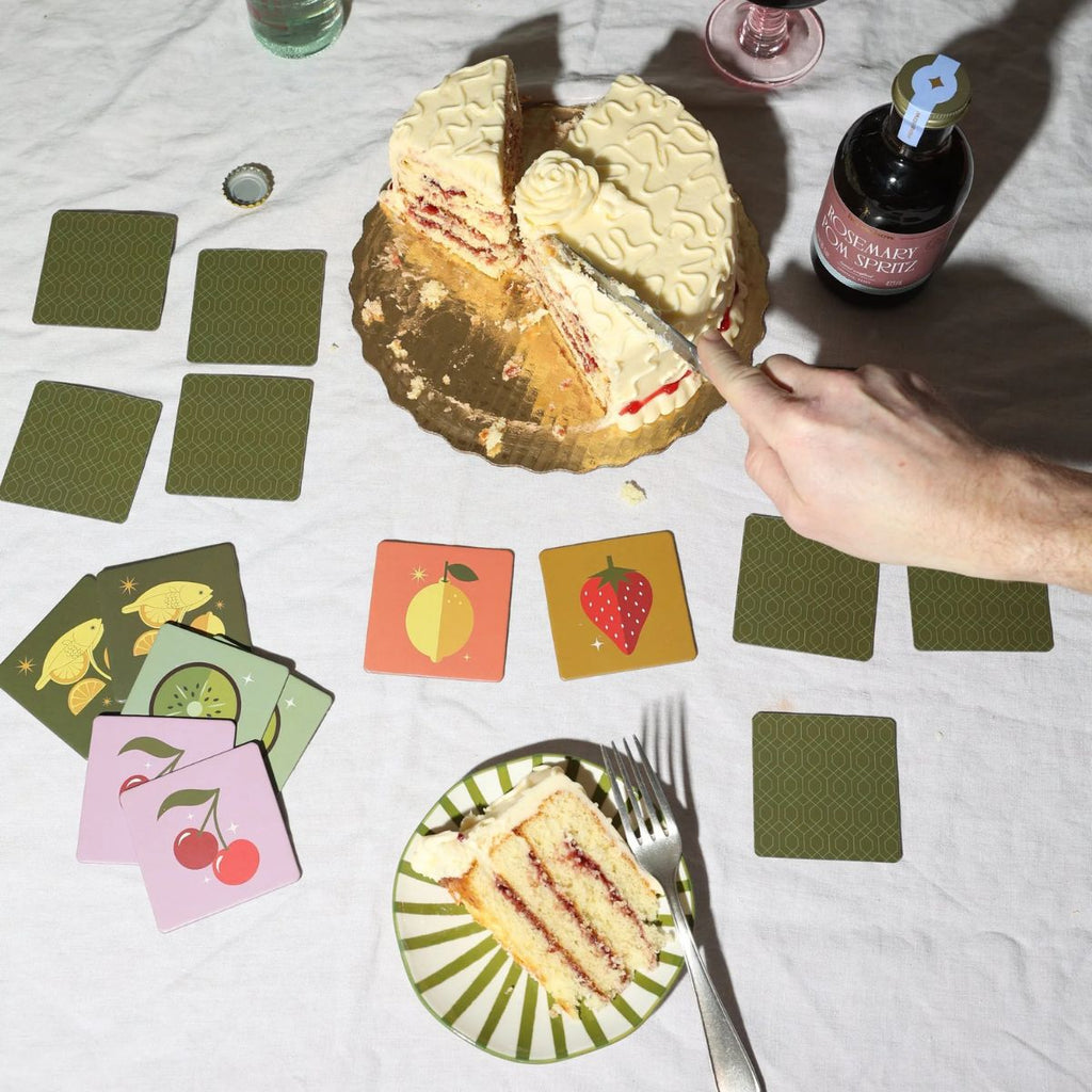 Layered cake with a slice taken out, surrounded by playing cards on a table.