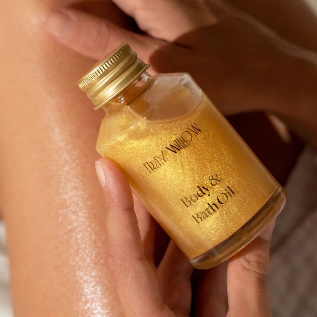 Gold bottle of 'Stray Willow' body and bath oil held by a hand.