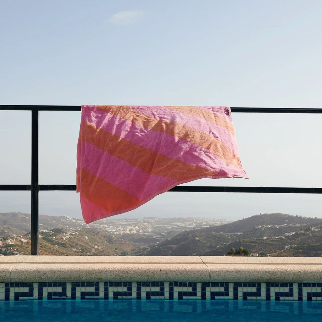 Pink and orange towel hanging over a railing with a scenic view in the background