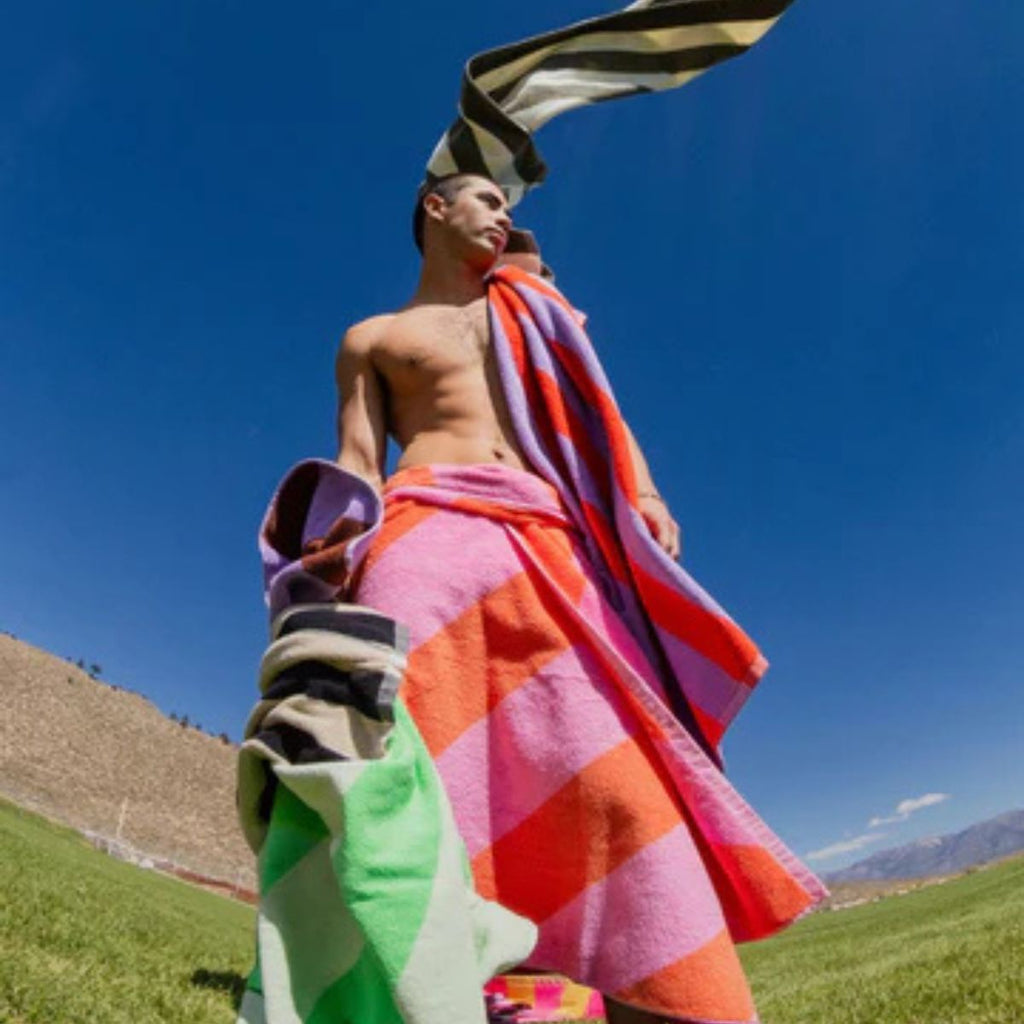 Person holding colorful towels against a blue sky