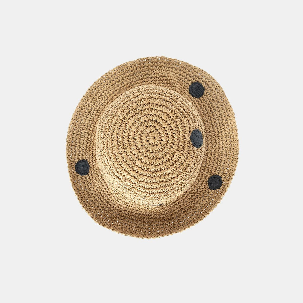 Beige straw hat with black dots on a light gray background