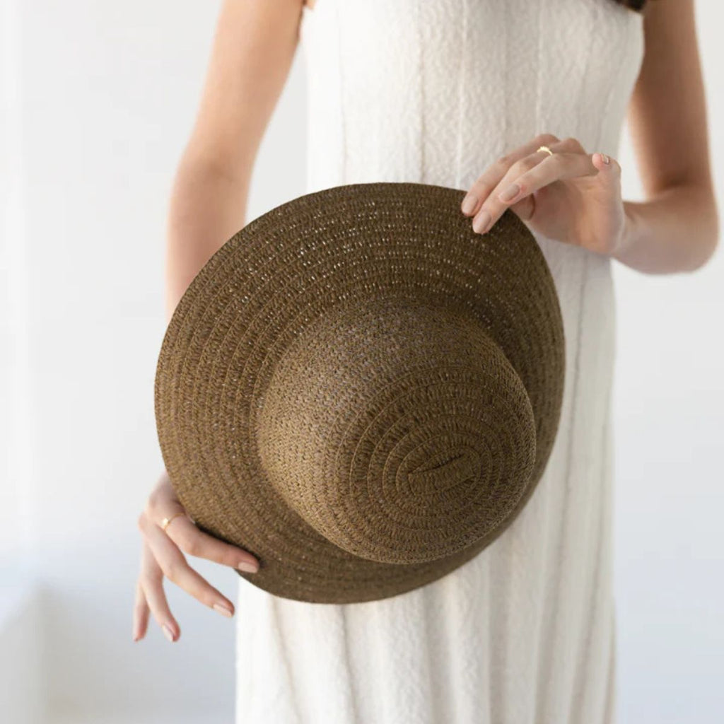Brown straw hat held by a person against a white background