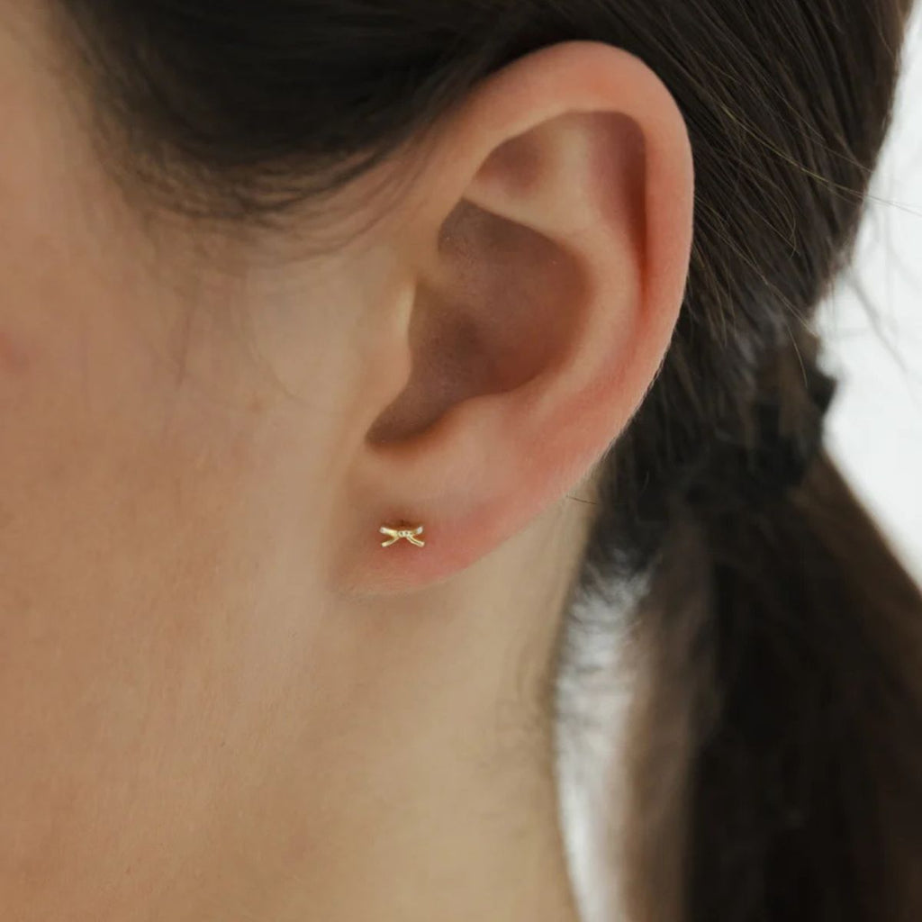Gold earring on a person's ear with a blurred background