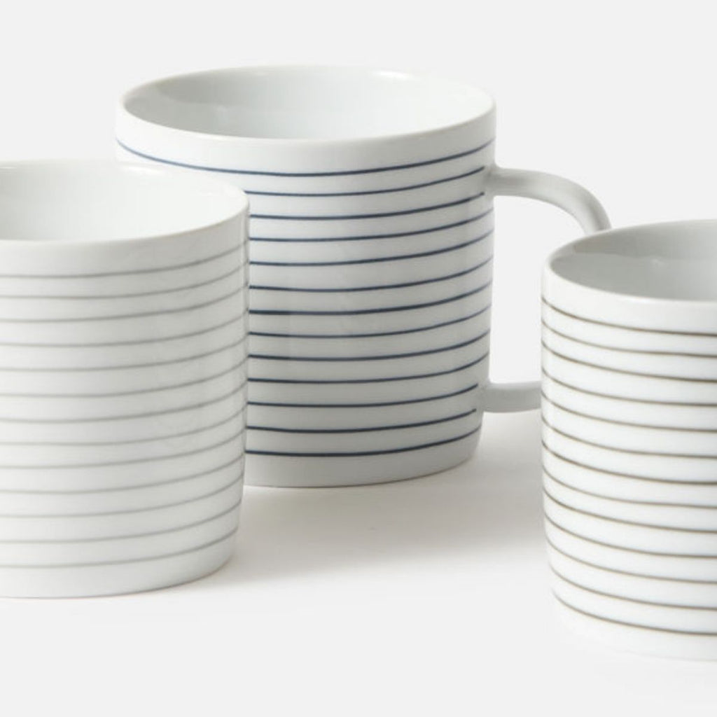 Set of white mugs with blue stripes on a white background