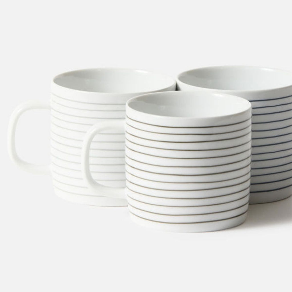 Set of white ceramic mugs with black stripes on a white background