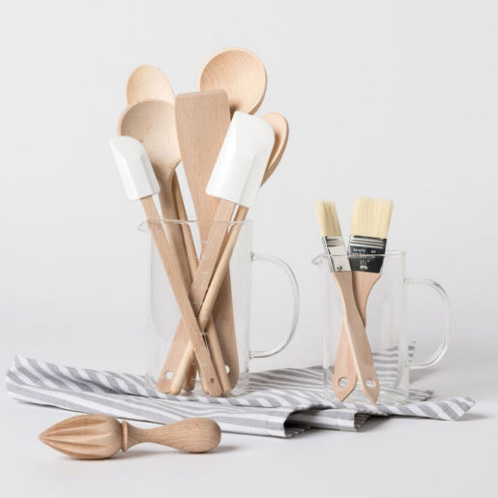 Set of wooden kitchen utensils including spatulas and a juicer on a light background.