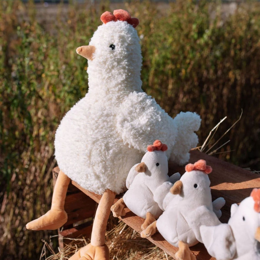 Plush chicken toys on a wooden cart with a natural background