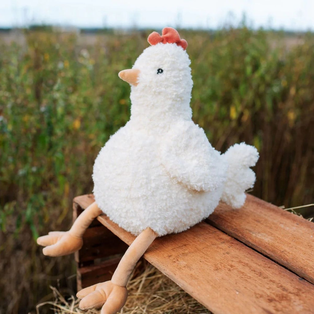 White plush chicken toy on a wooden surface with a natural background