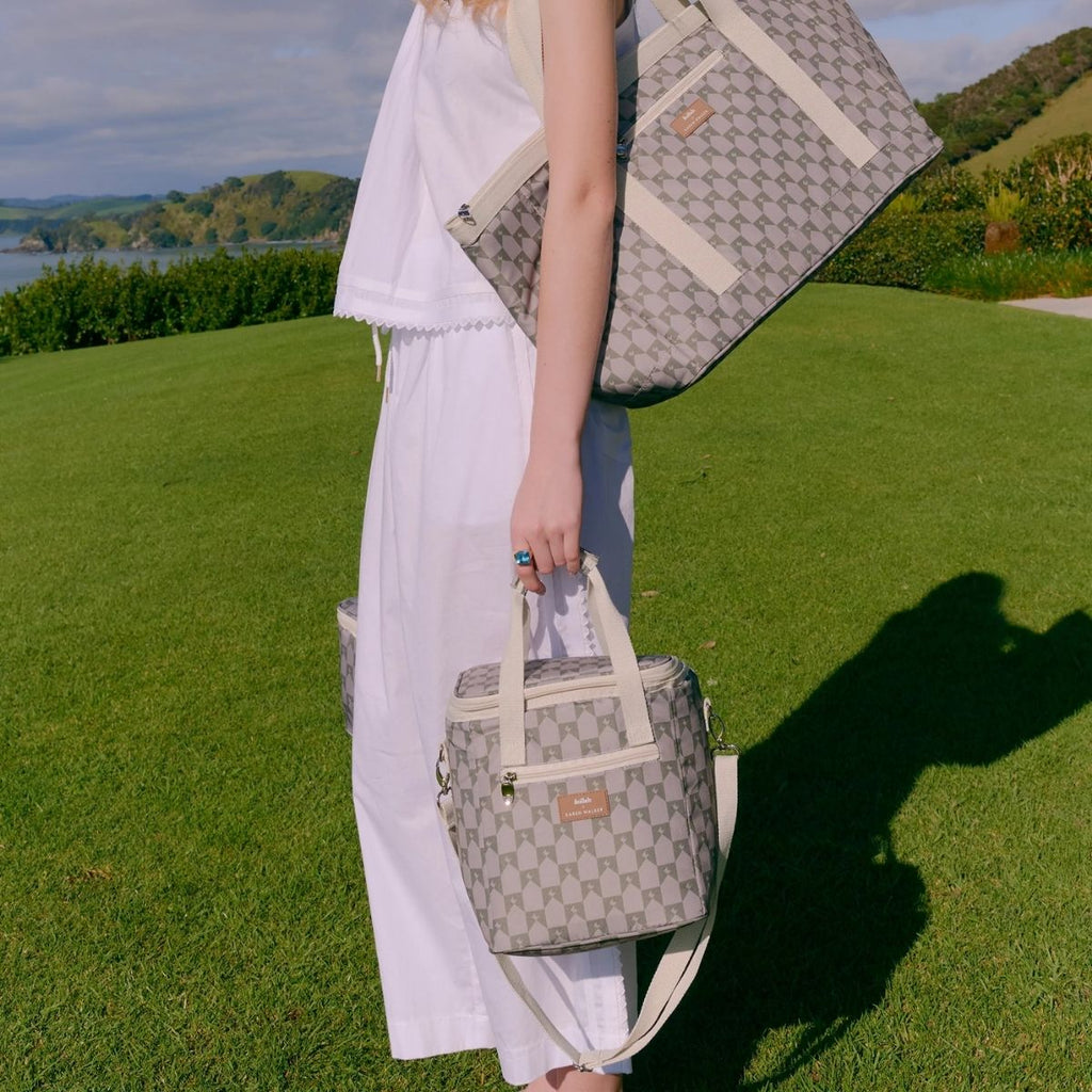 Person holding two patterned bags outdoors with a scenic background