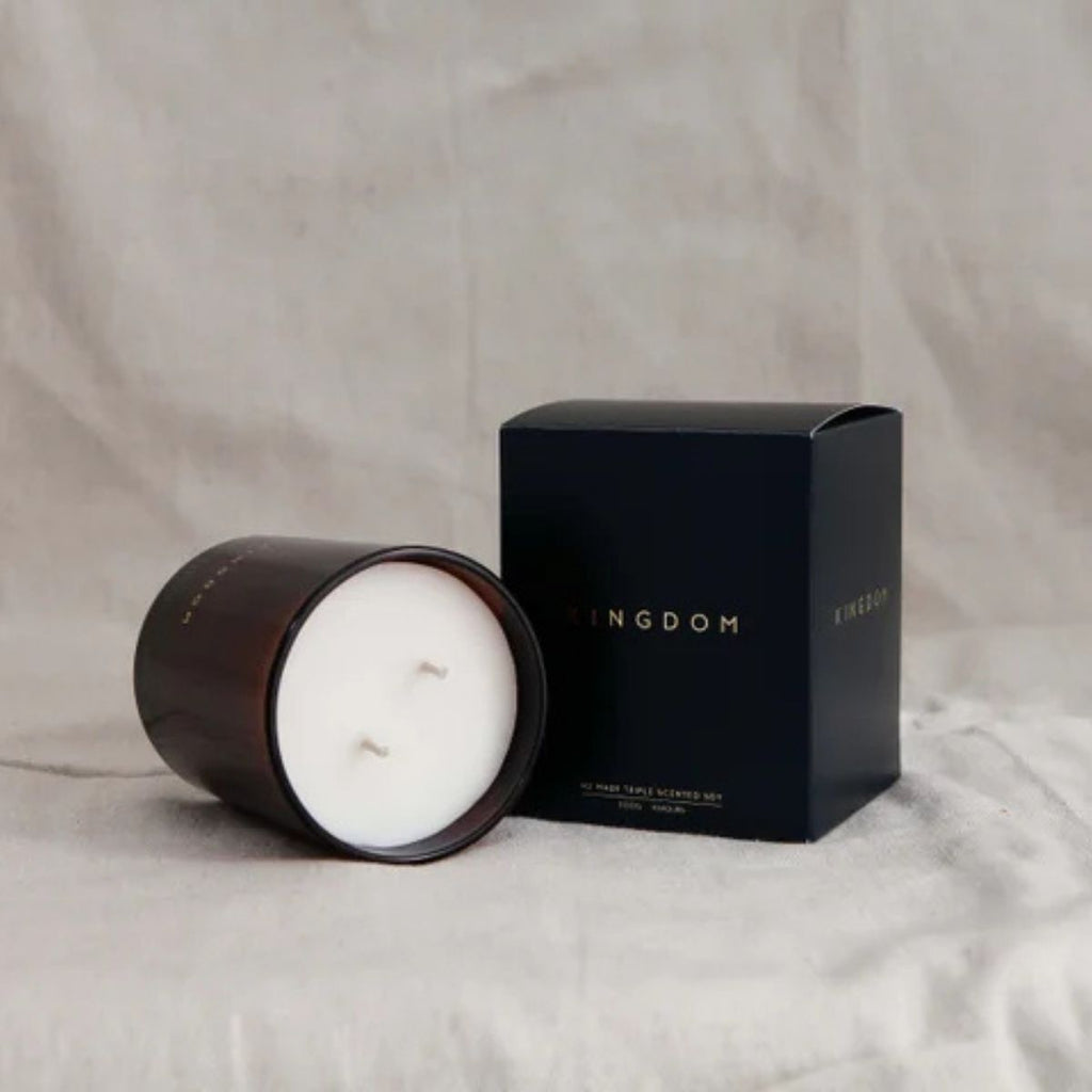 Candle and its packaging with 'Kingdom' branding on a neutral background