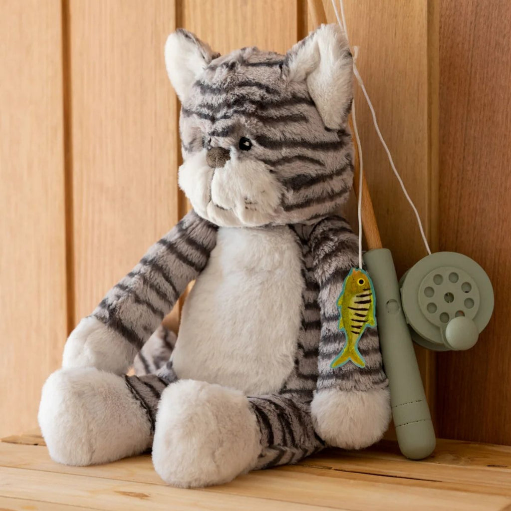 Plush toy cat with fishing rod and reel on a wooden surface