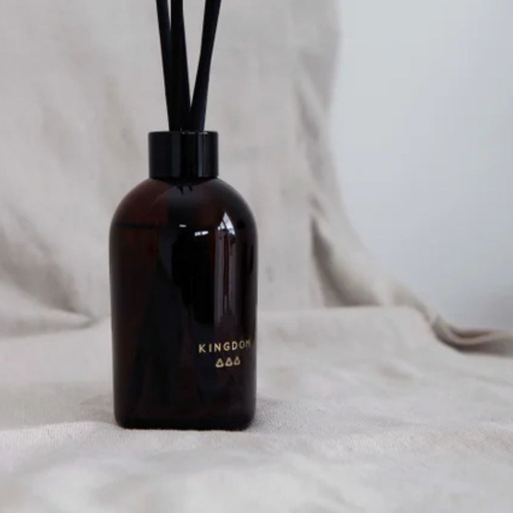 Black diffuser bottle labeled 'Kingdom' on a light fabric background