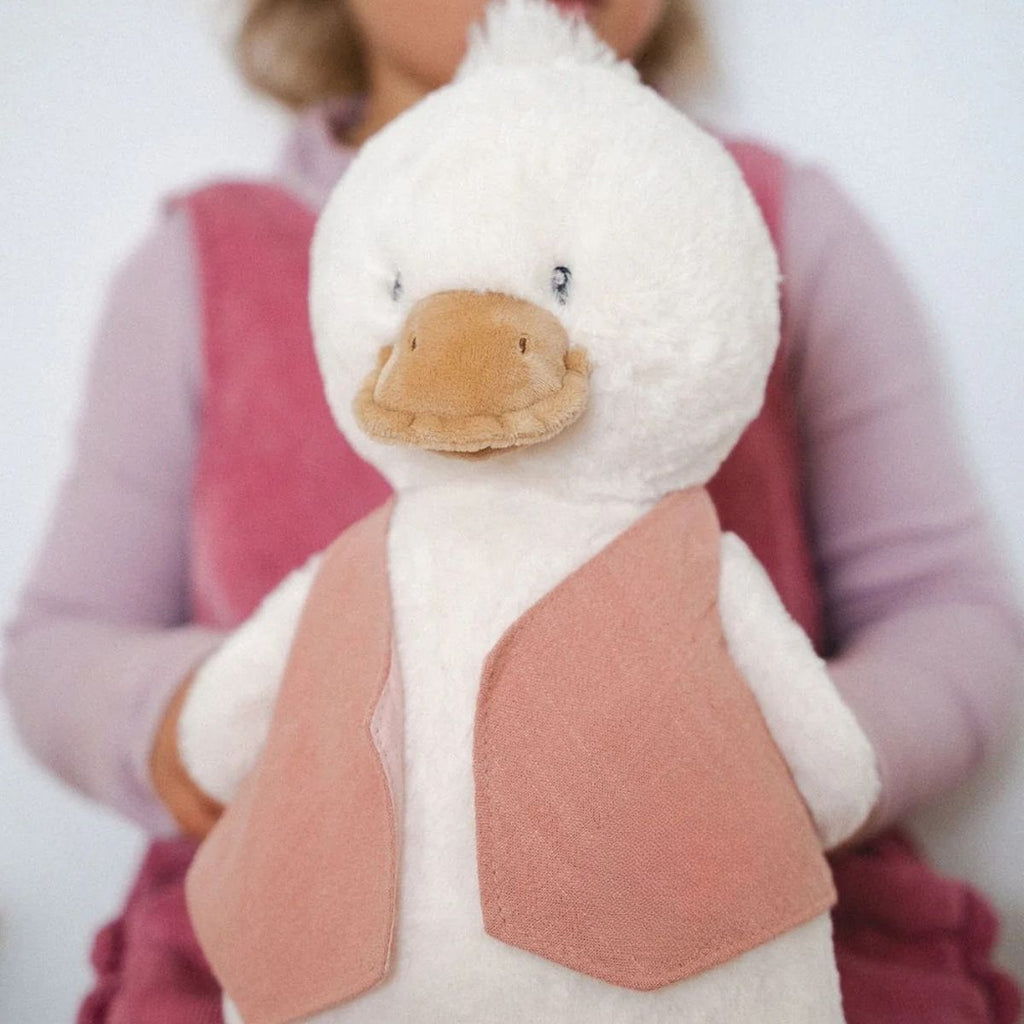 Plush duck toy held by a person wearing a pink backpack
