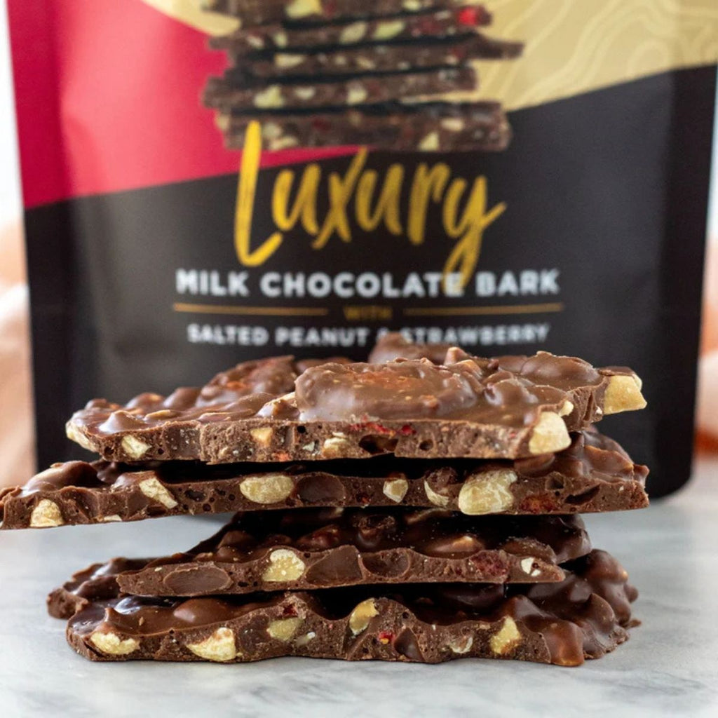 Stack of chocolate bark with a 'Luxury Milk Chocolate Bark' packaging in the background.