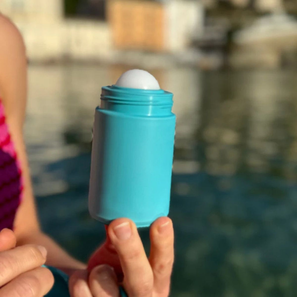 Person holding a blue silicone roller sunscreen with a blurred background