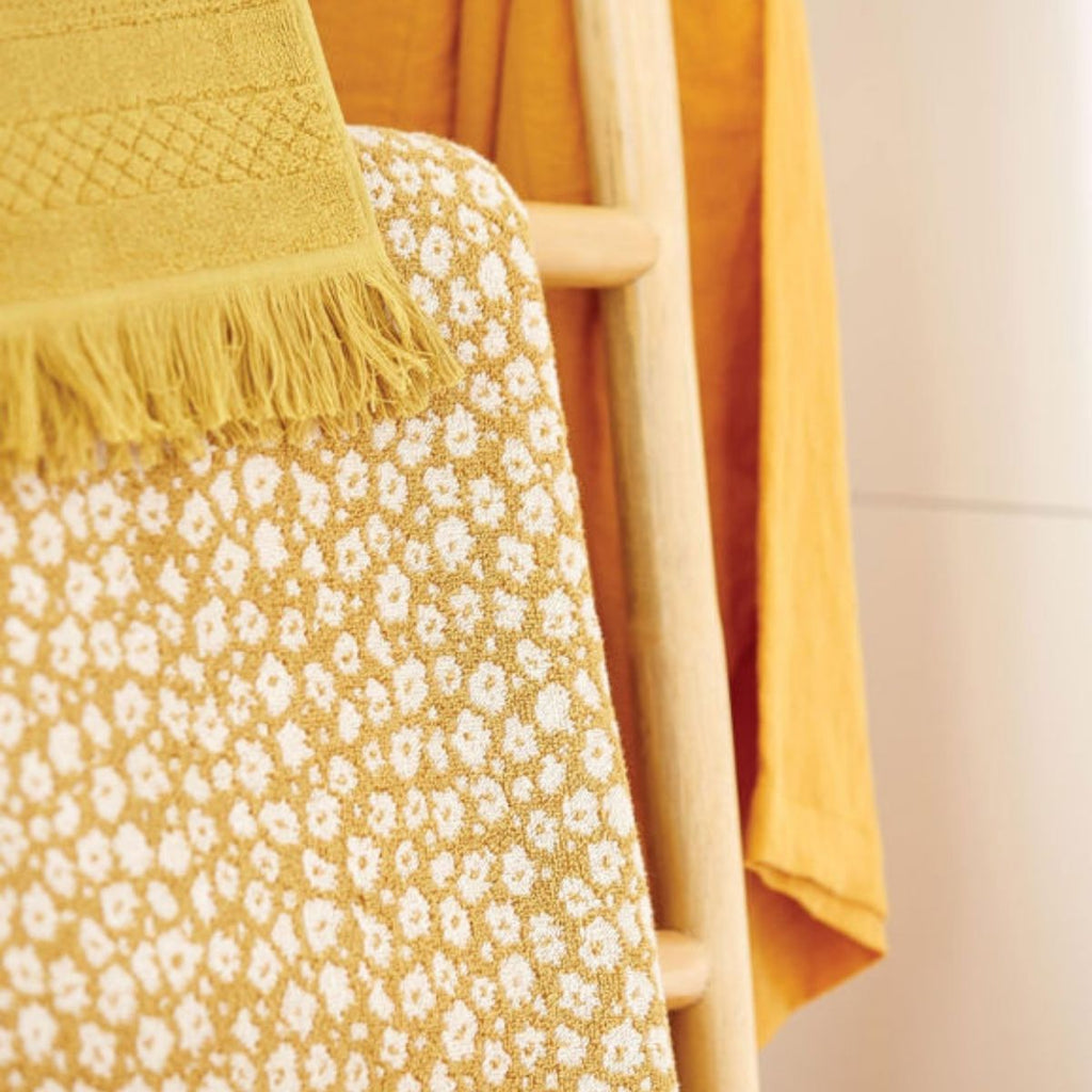 Yellow floral-patterned fabric draped over a wooden chair with a neutral background