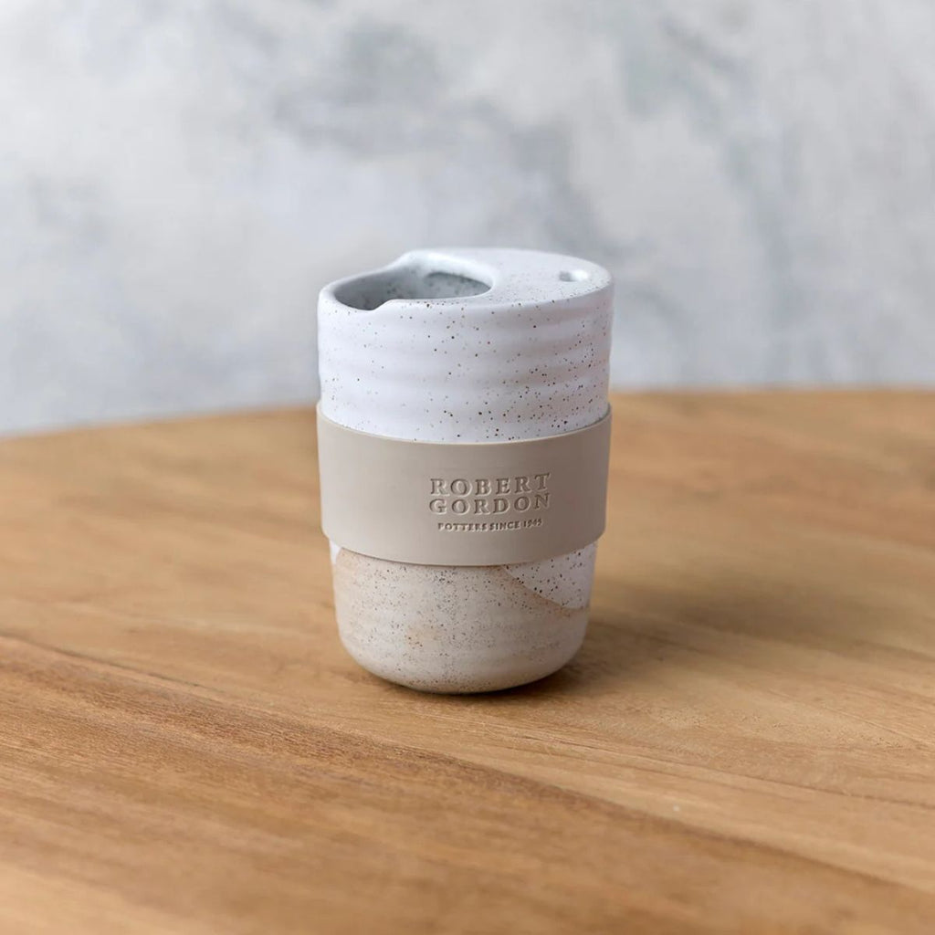 Speckled ceramic cup with beige base on a wooden surface