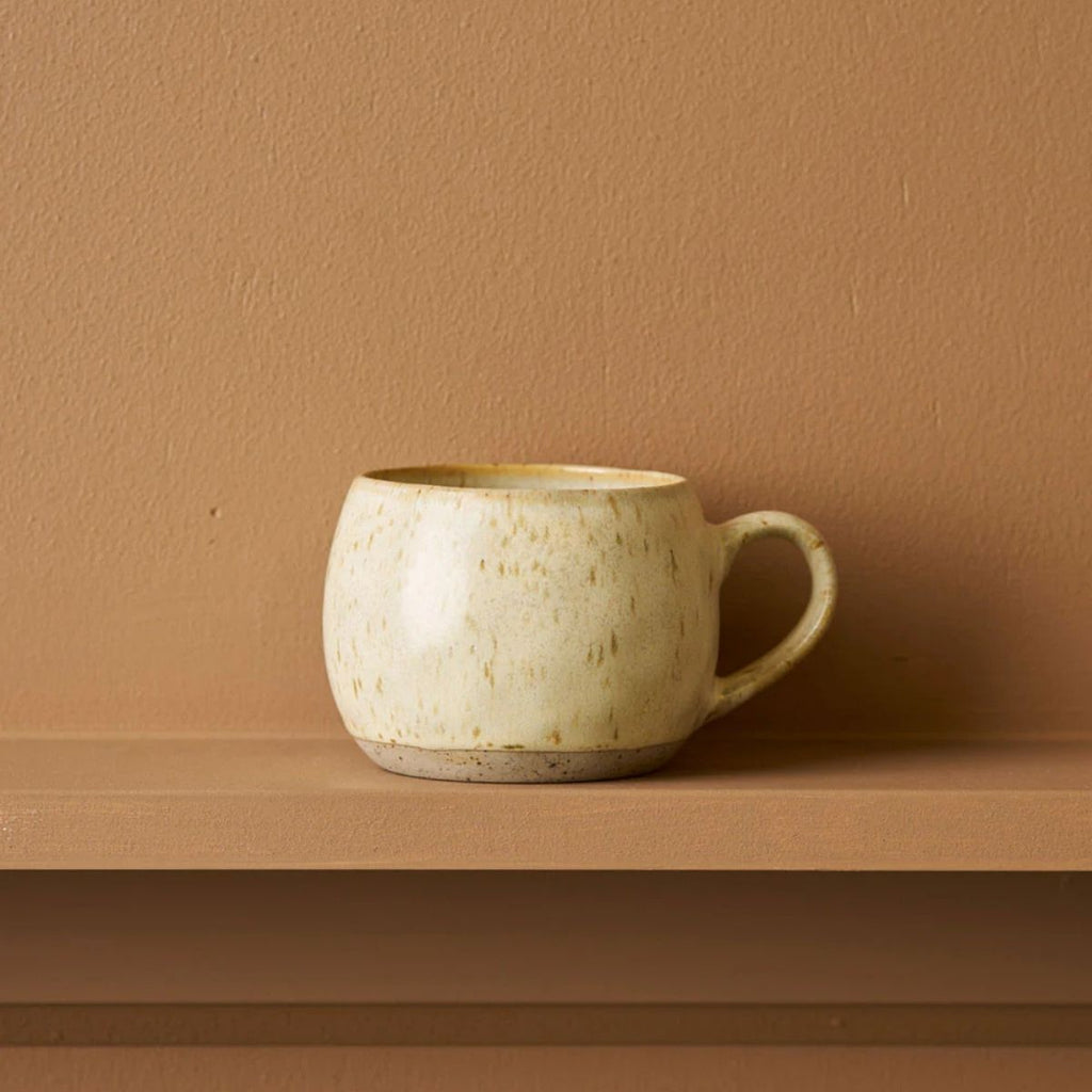 Beige ceramic mug on a brown surface with a matching brown wall background