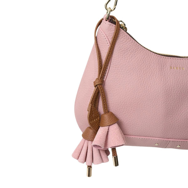 Pink handbag with a brown strap and tassel on a white background