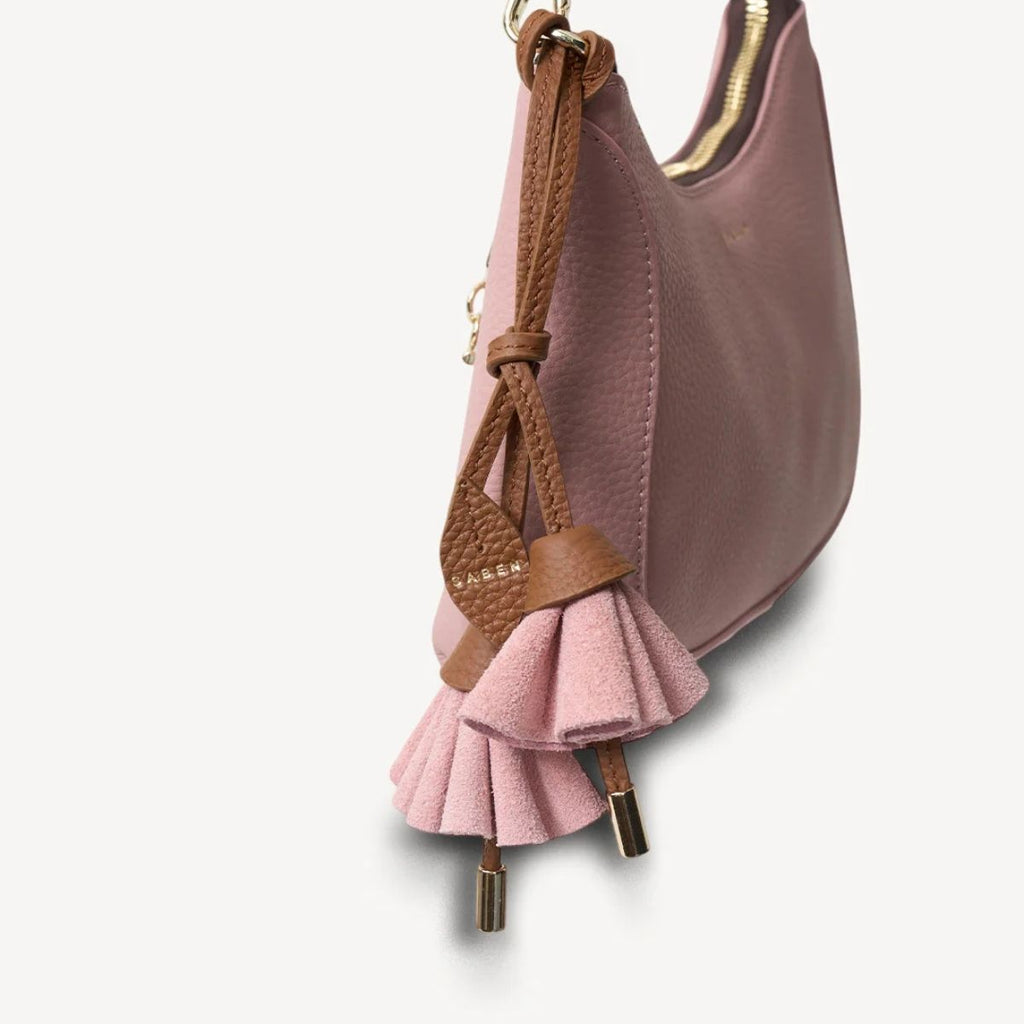 Pink handbag with ruffled detail and brown strap on a light gray background