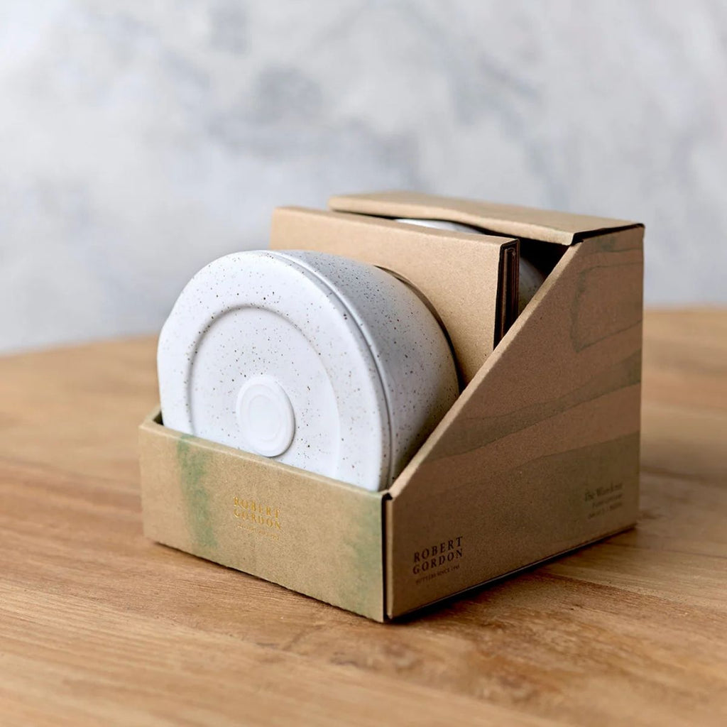 White circular object in a cardboard box on a wooden surface with a light gray background