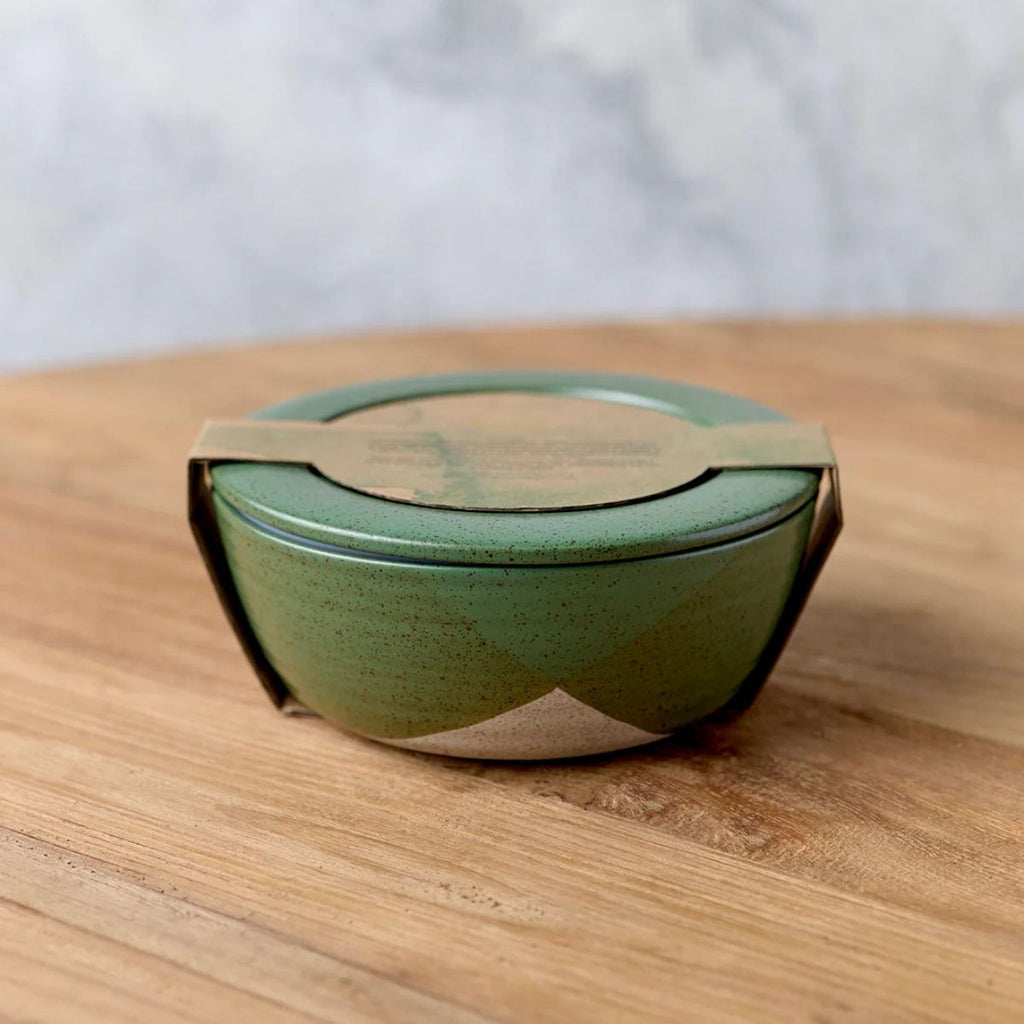 Green ceramic bowl with lid on a wooden surface