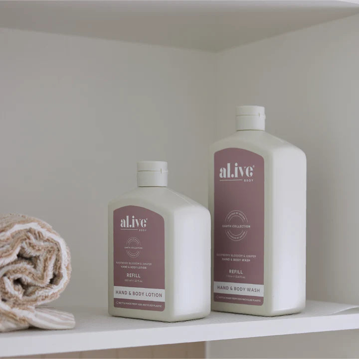 Two bottles of 'alive' hand and body products on a shelf with a towel.