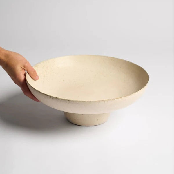 Hand holding a ceramic bowl on a light gray background