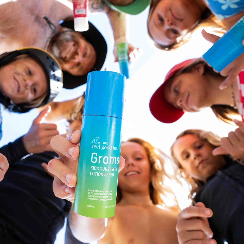 Group of people holding a blue and green 'Grooms' kids sunscreen lotion pump.