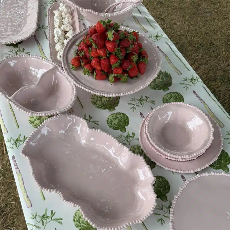 Set of melamine dishes with strawberries on a tablecloth with green leaf pattern
