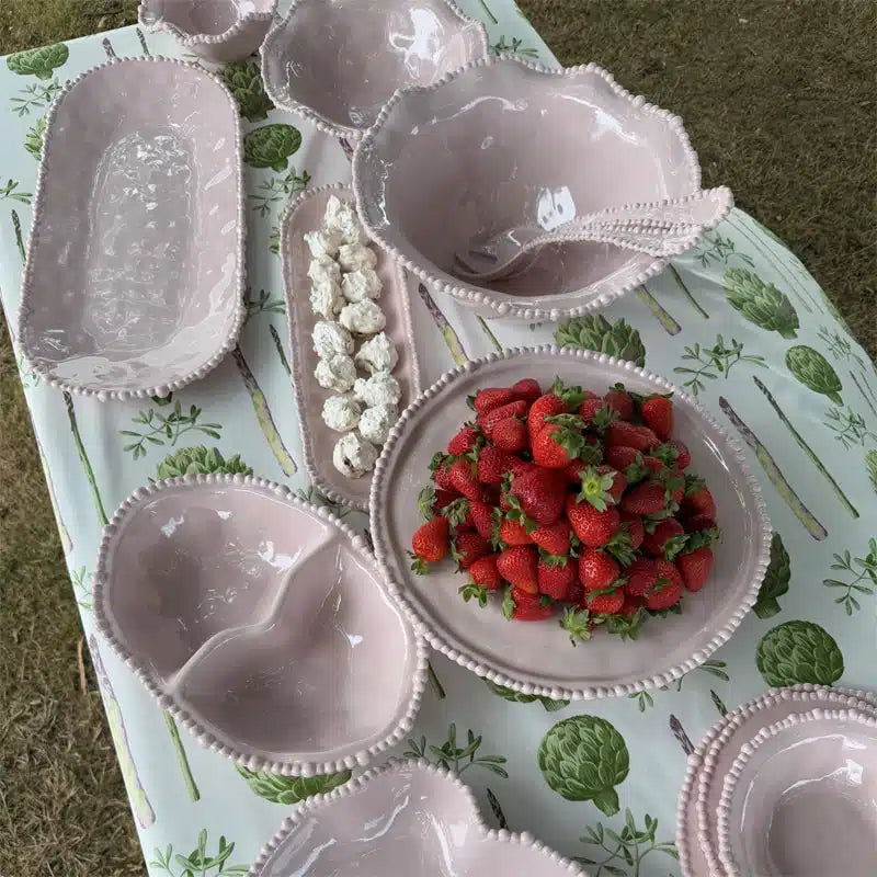 Set of melamine dishes with strawberries on a tablecloth with green leaf pattern