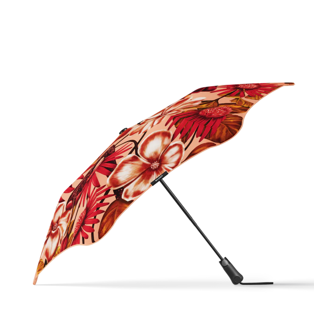 A red, white and orange floral print and black handle blunt brand umbrella
