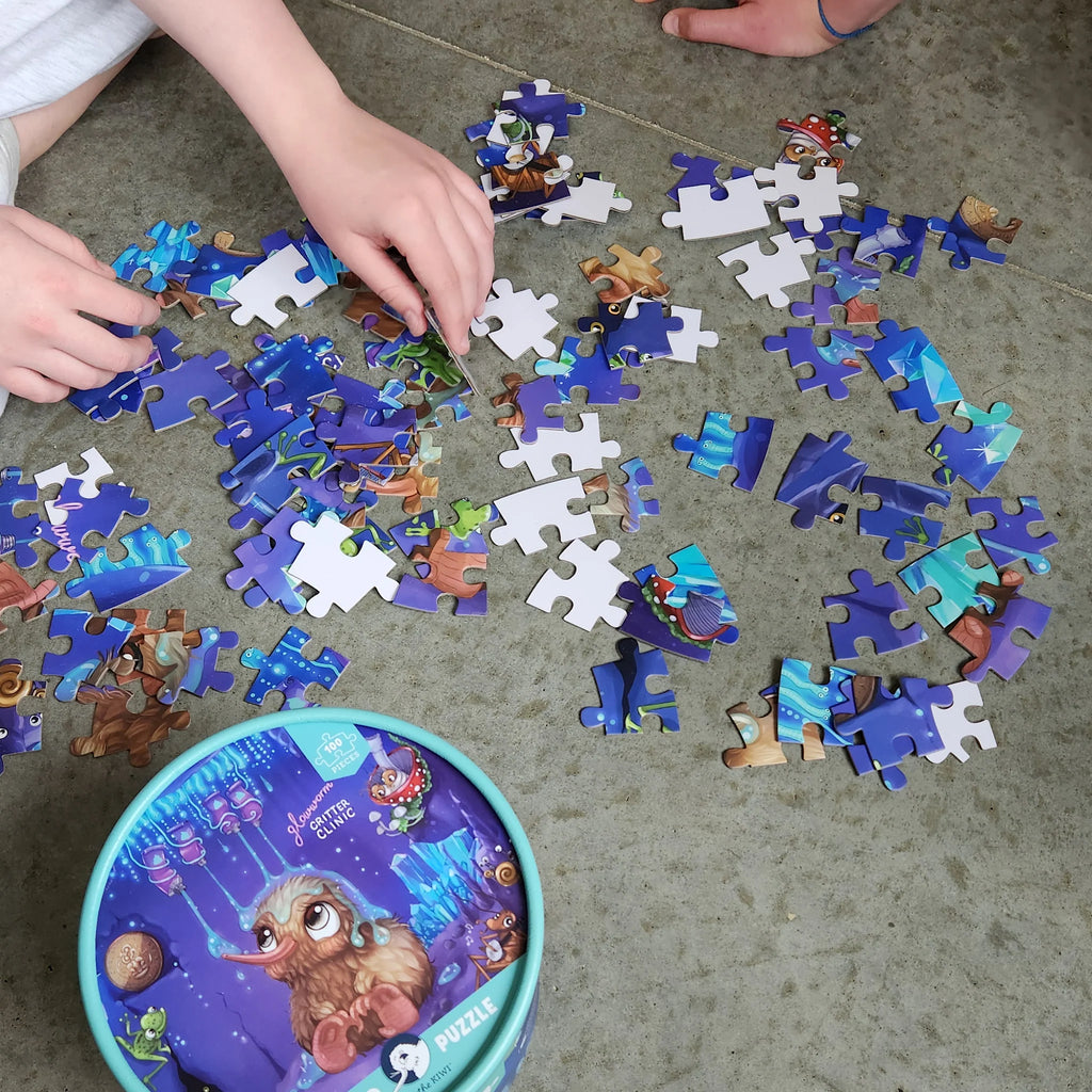 Children playing with a puzzle on the floor next to a container labeled 'Pebbles'.