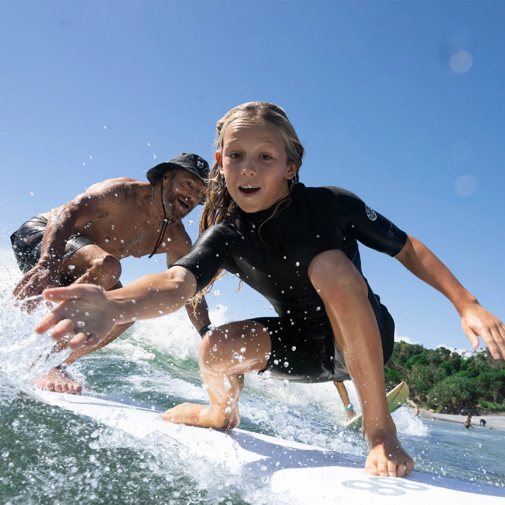 Two people surfing on a sunny day with clear blue sky.