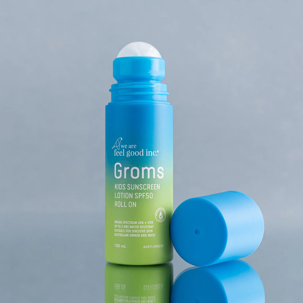 Blue and green roll-on sunscreen bottle with 'Groms' branding on a gray background