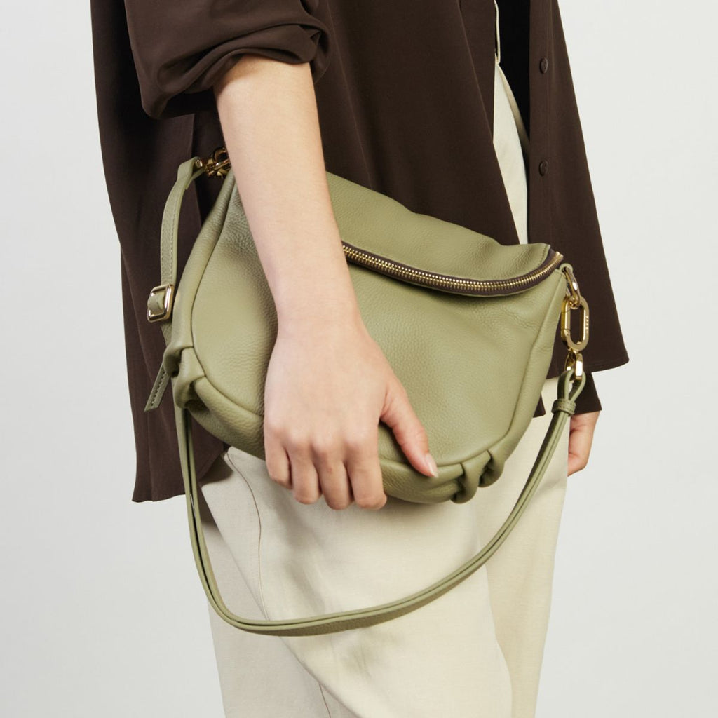 Person holding a green handbag against a neutral background