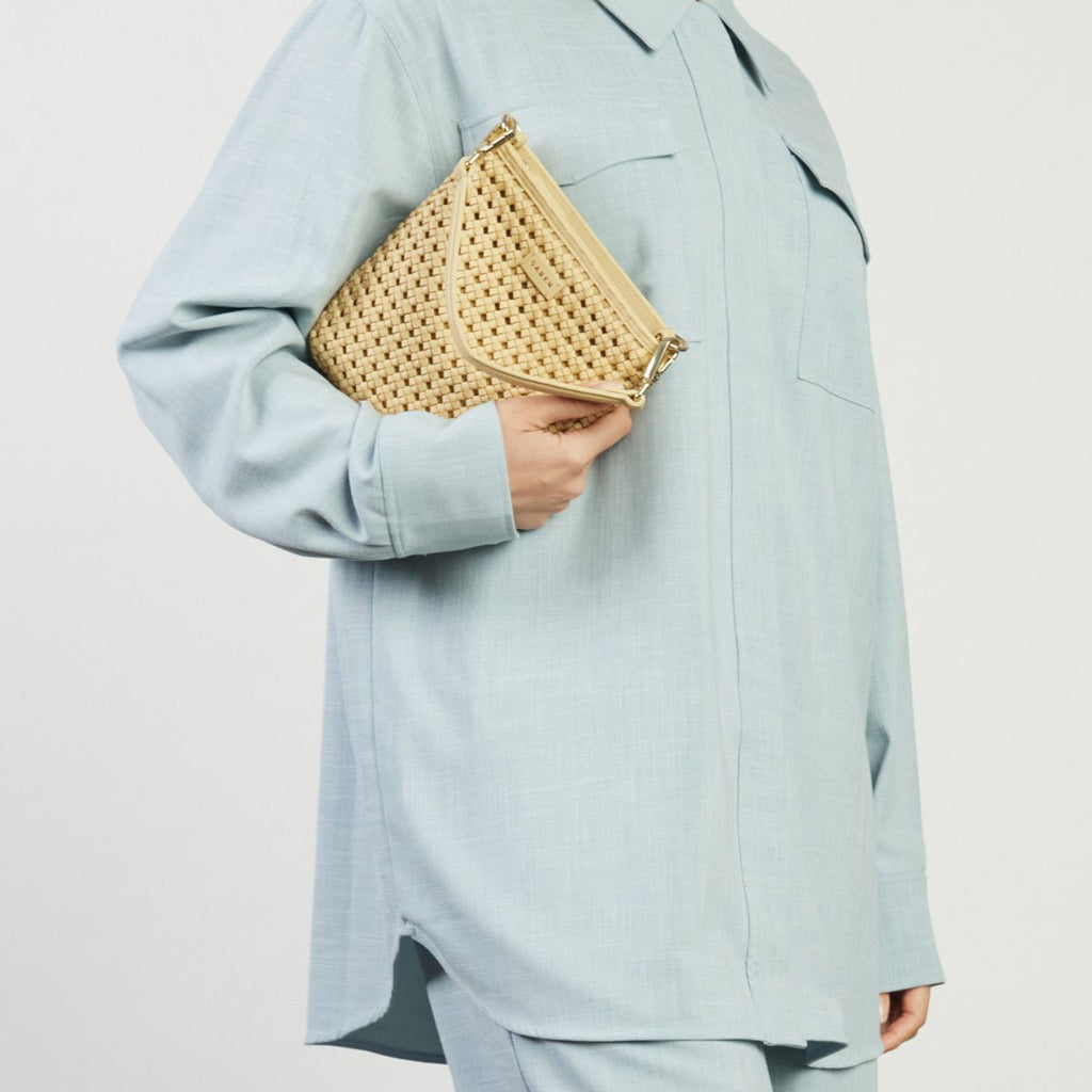 Person holding a gold clutch against a light gray background